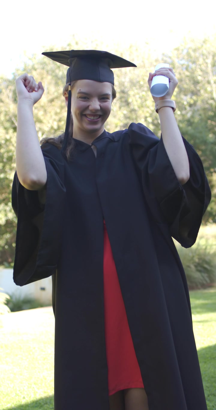 Video verticale: Laureata dopo la cerimonia che esulta, alzando il diploma e festeggiando nel campus con il tocco.