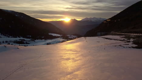 drone traveling above the snow through the cortals valley in andorra, the light of the sunset is reflected in the snow, in the background the pyrenees