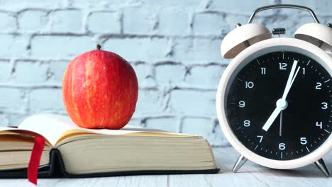 apple, book and clock on a desk