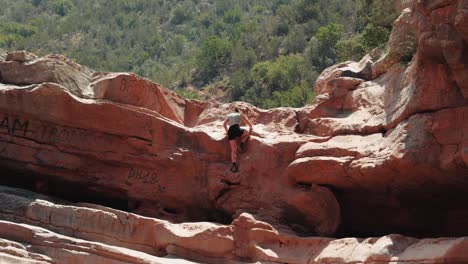 young caucasian woman climbing up rocks in paradise valley, agadir, morocco