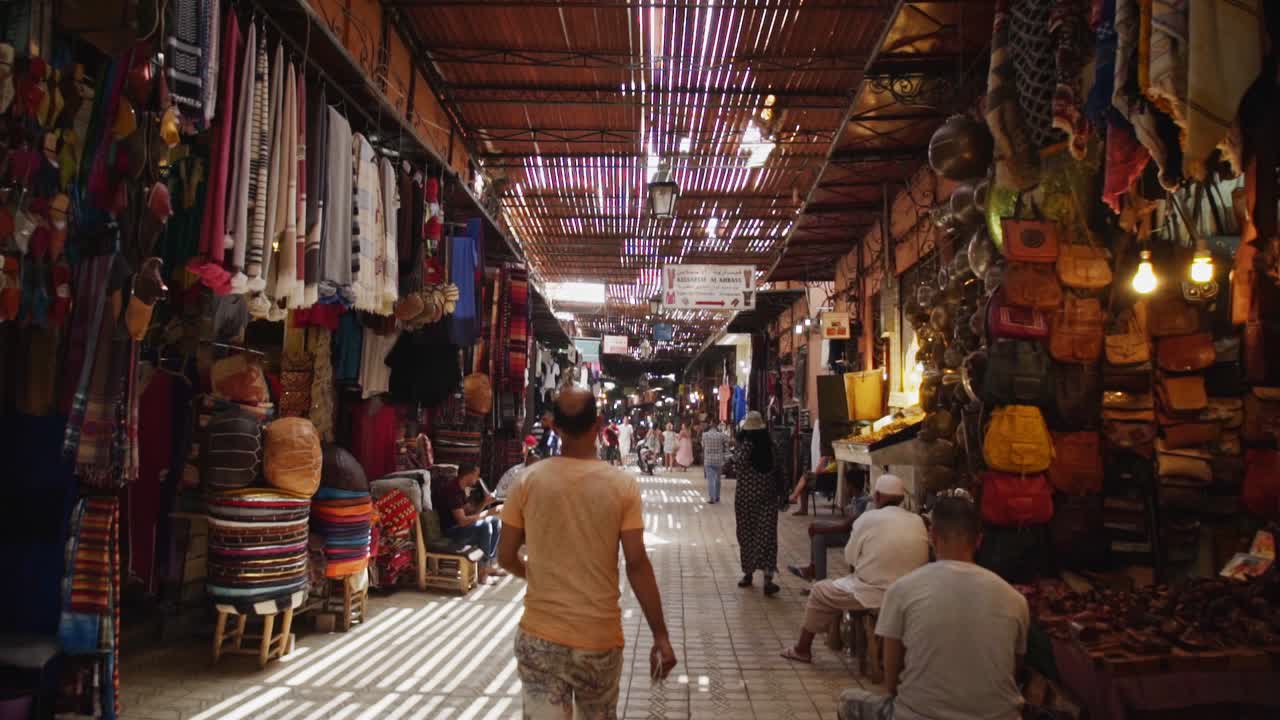 People strolling around the ancient alleyways of the Medina bazaar in Marrakesh Morocco. Handheld shot.