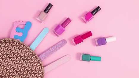 conjunto de herramientas de manicura se mueve en kit sobre un fondo rosa pastel.