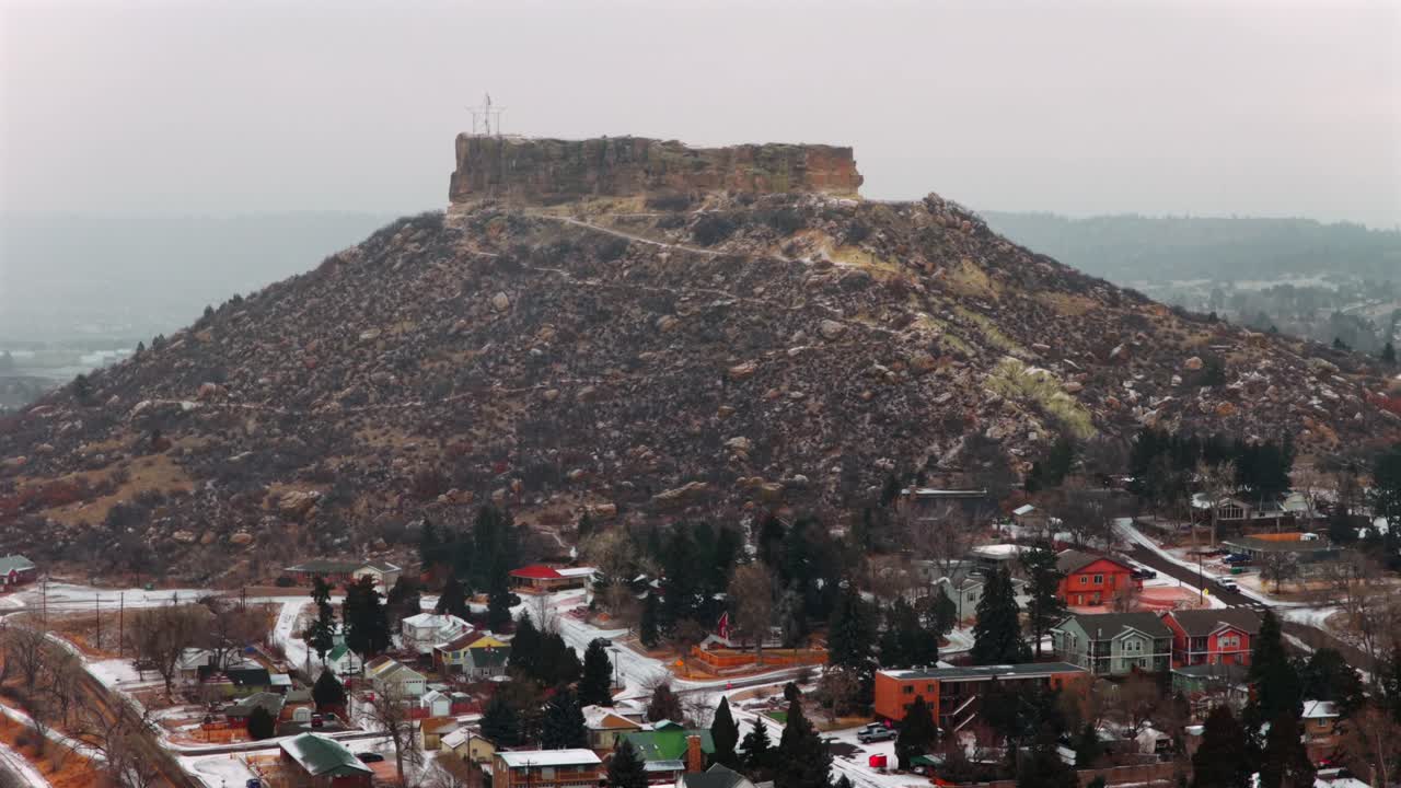 Kışın Castle Rock dönüm noktası, Colorado şehir merkezinin havadan drone ile çekilmiş manzarası. Front Range'deki karla kaplı mesa, arabalar, binalar ve mahalleler. Karlı, soğuk bir sabah, kar yağıyor, bulutlu güney Denver şehri, sağa doğru dairesel hareket.