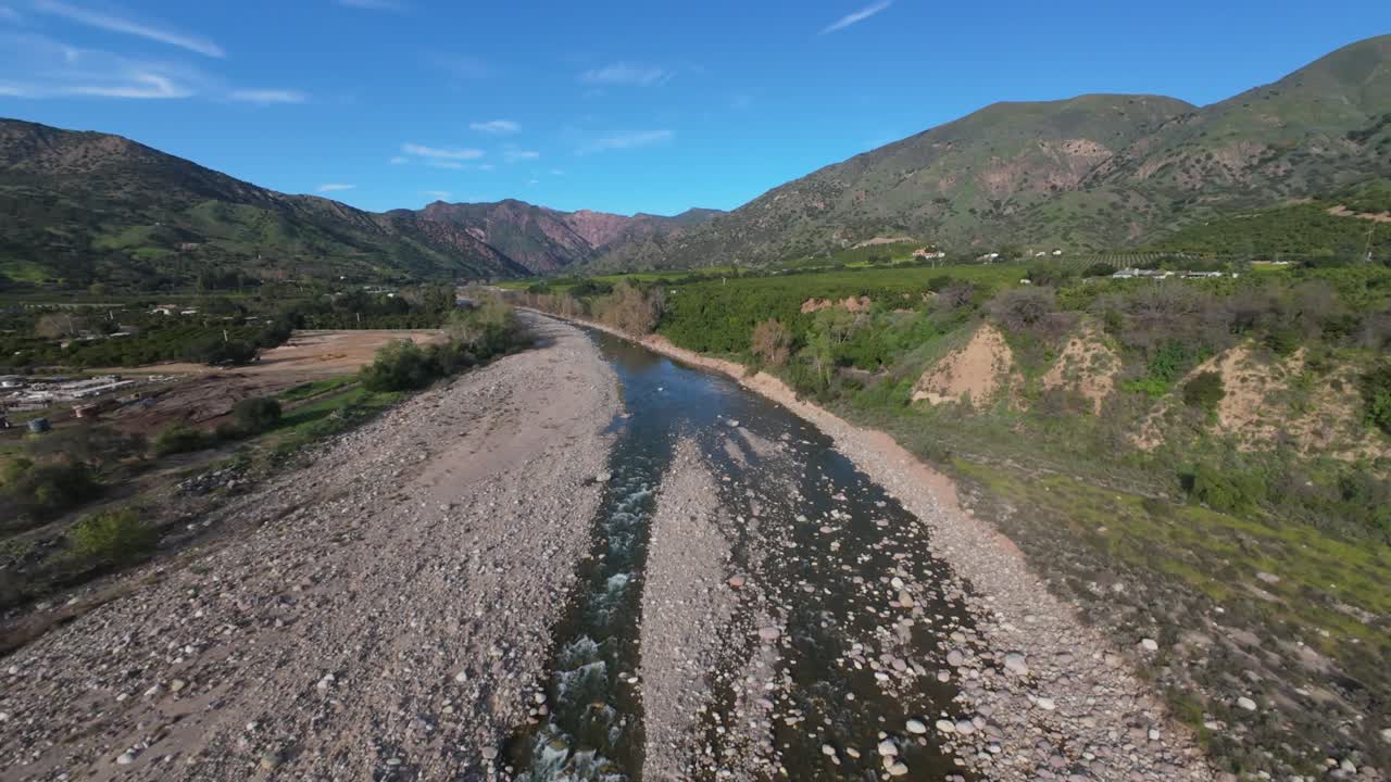 Vista aerea con un drone che vola sopra un ruscello con grandi rocce tra le fattorie in una bella giornata.