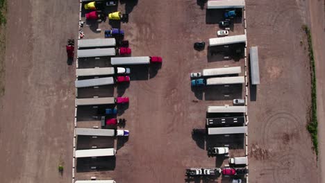 top down aerial of yard parking lot with semi trucks and trailers - reefers, dry van, flatbeds, stingers, bob tails