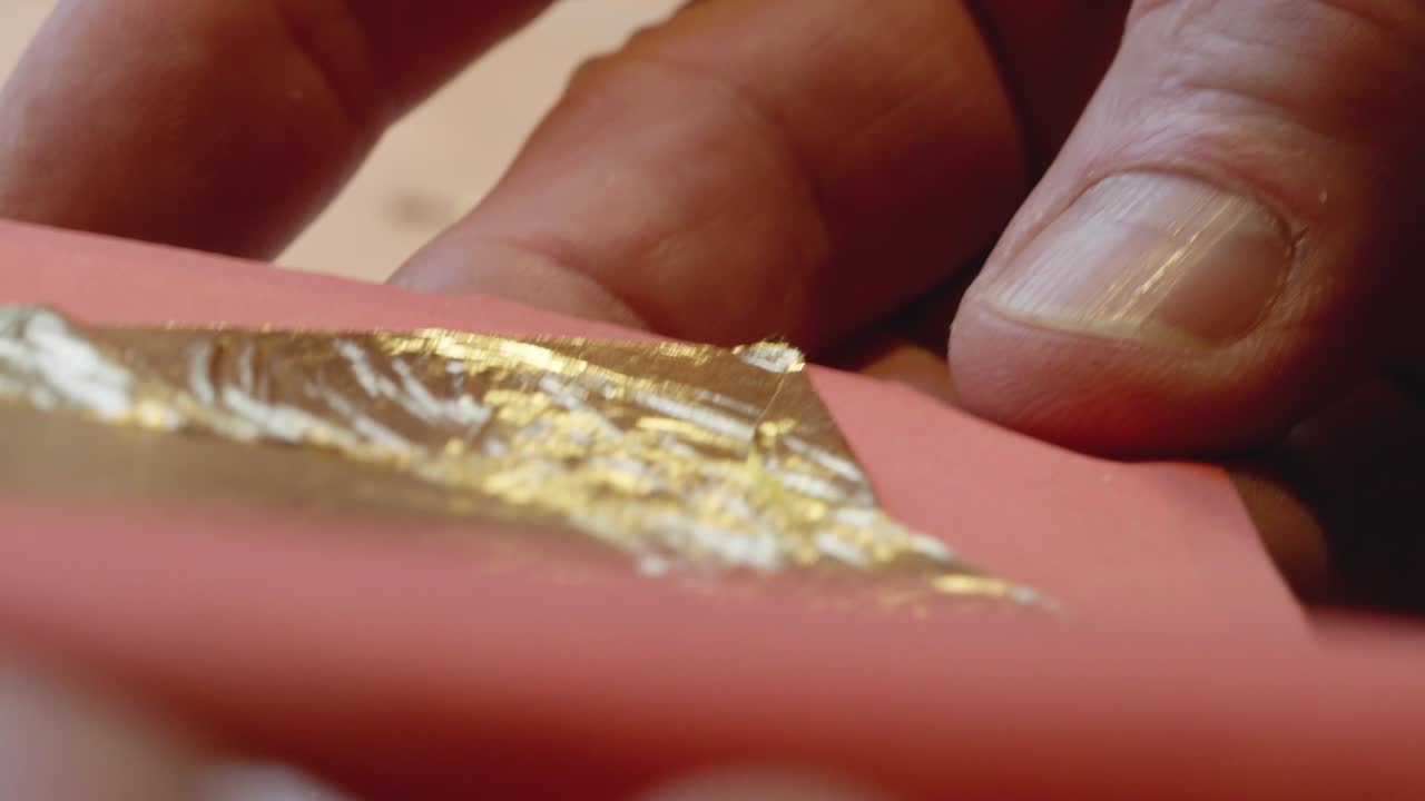 primer plano del artista que muestra una hoja de oro