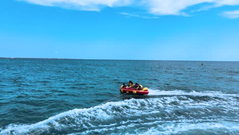 people on an inflatable tube being towed on the ocean
