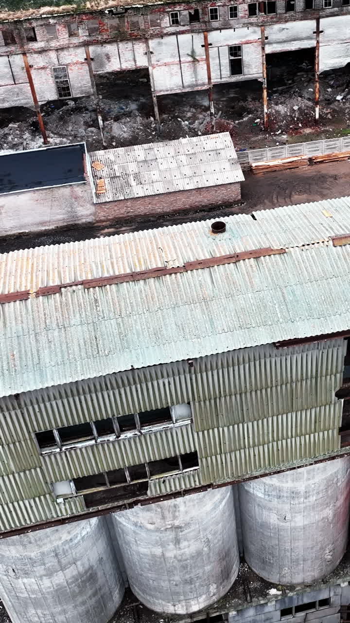 Old wrecks of chemical plant locality. Broken walls with huge holes and debris on the ground. Aerial view. Vertical video