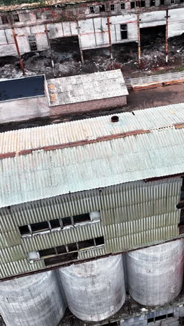 old wrecks of chemical plant locality. broken walls with huge holes and debris on the ground. aerial view. vertical video
