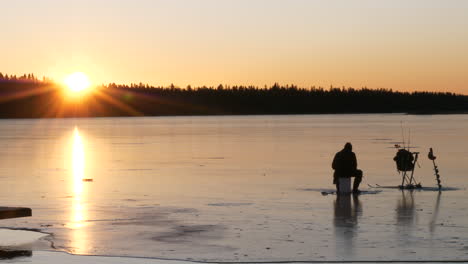 Silhouette-man-fishing-wintertime,-Sunrise-and-snow,-Static-shot