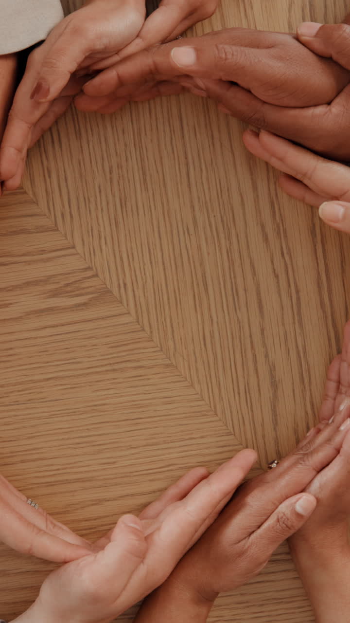 Diverse Hands Form a Heart Shape on a Wooden Table