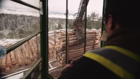 first person pov blue collar tradesman operates industrial timber logging manipulator arm claw tractor from inside cabin with joystick-1