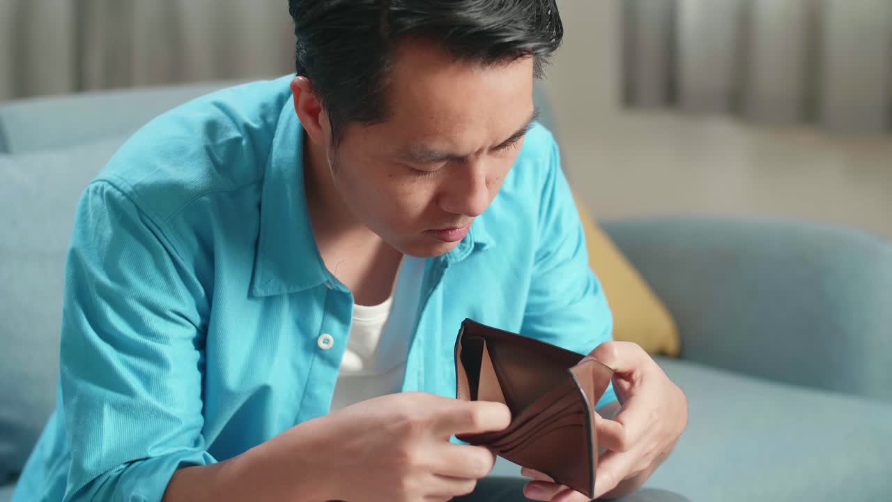 머리를 흔들기 전에 지갑에 돈을 확인하는 노트북을 가진 아시아 남자의 클로즈업