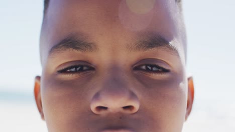 face of happy african american boy smiling at camera on beach