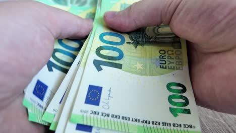 person counts out 100 euro banknotes money