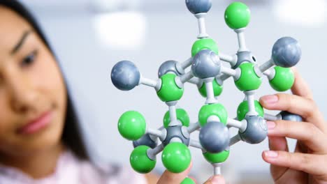 schoolgirl experimenting molecule model in laboratory at school