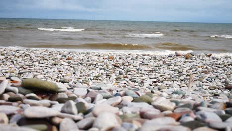 Schaumig-Brechende-Meeresbrandung-Kieselstrand-Küste-Flut-Beruhigende-Bunte-Steine-Nahaufnahme-Rechts-Dolly-Shot