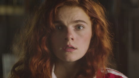 a nervous red-haired girl looks at the camera and stares