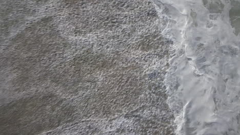 aerial drone shot of sea waves crashing in the beach