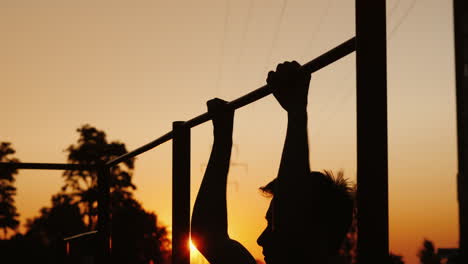 training in the city - a young man pulls up on a horizontal bar street training and sports among you