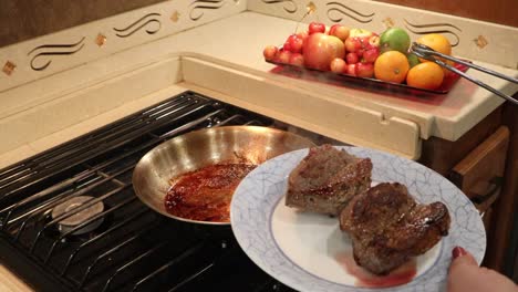 Woman-removing-cooked-steaks-from-heated-skillet-and-placing-on-plate