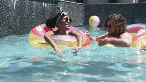 diverse couple, a young african american woman and caucasian man, enjoy pool time
