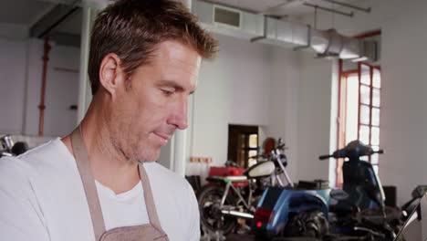 male mechanic using laptop in motorbike repair garage 4k