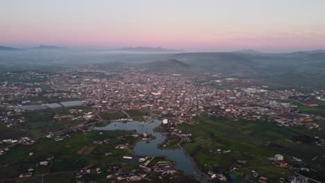 Aerial view of historic Mexican town at sunrise, with Almoloya lagoon in the center and background mountains