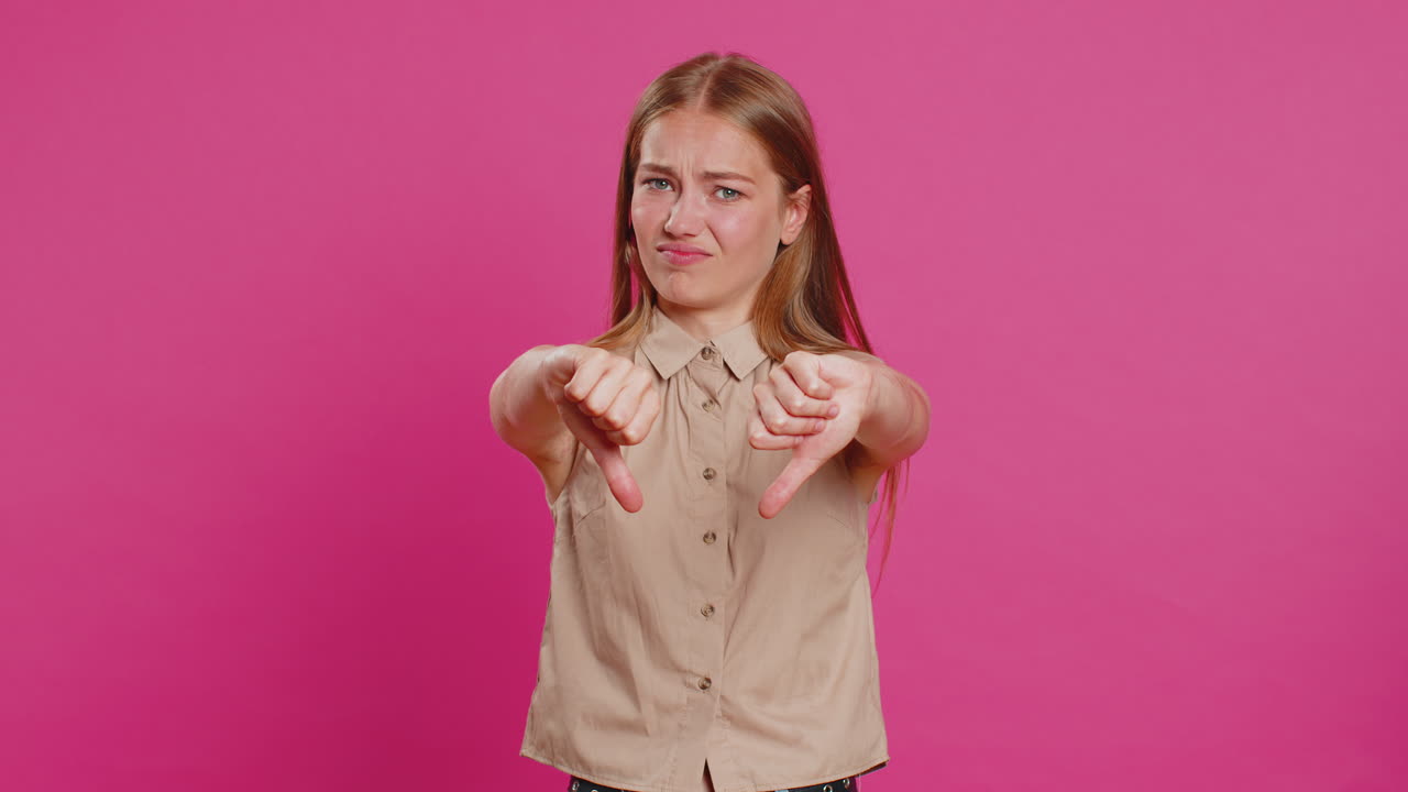 Upset attractive young woman girl showing thumbs down sign gesture disapproval dissatisfied dislike