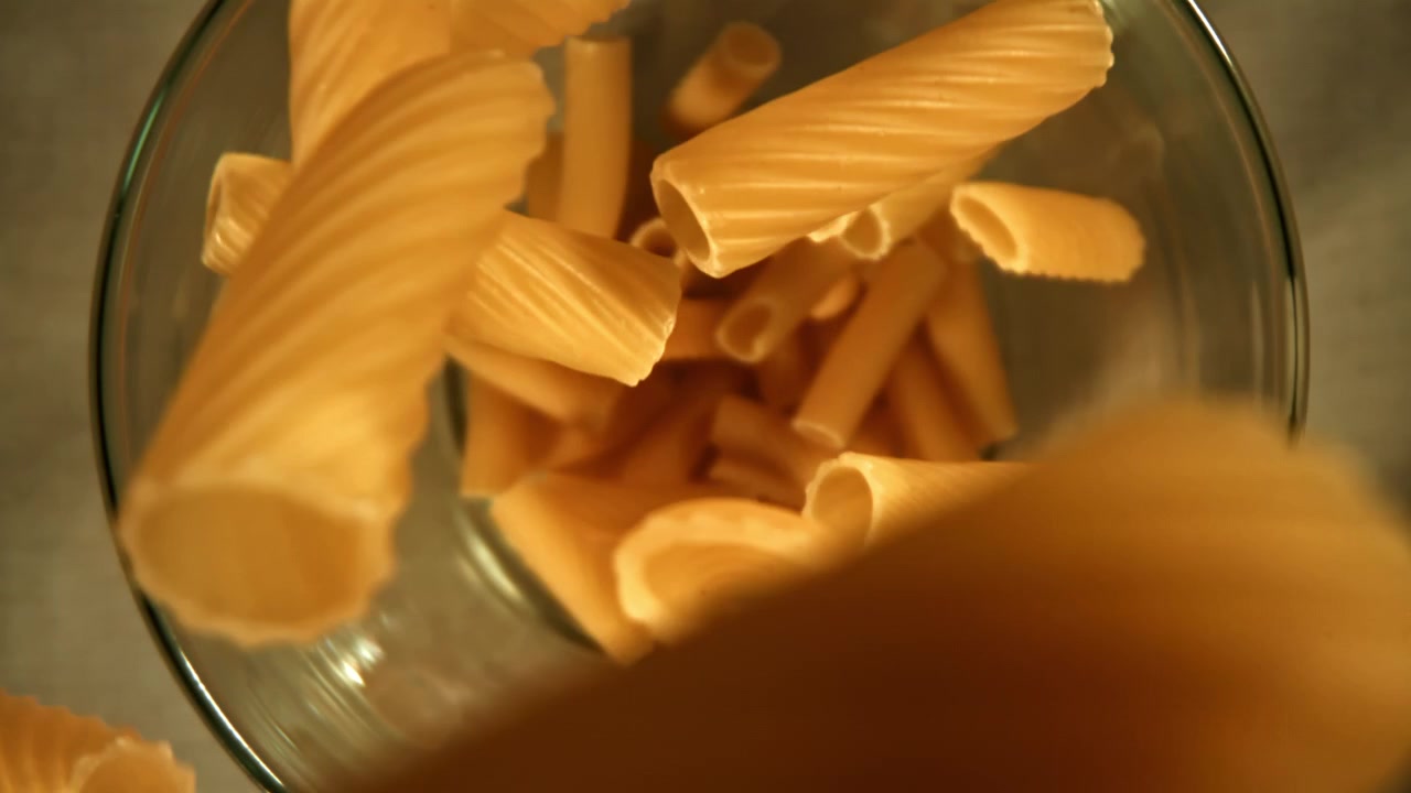 Pasta secca che cade in una ciotola di vetro al rallentatore