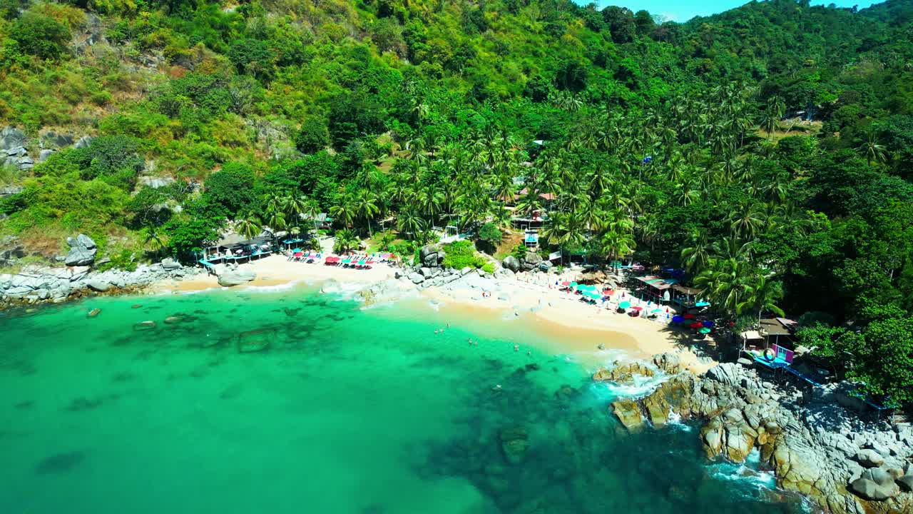 Vibrant umbrellas line this hidden Thai beach tucked between lush jungle hills and turquoise waters—an idyllic escape bursting with tropical charm.