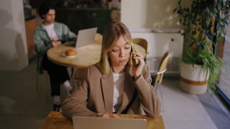 young businesswoman talking on the phone while working on her laptop in a coffee shop.