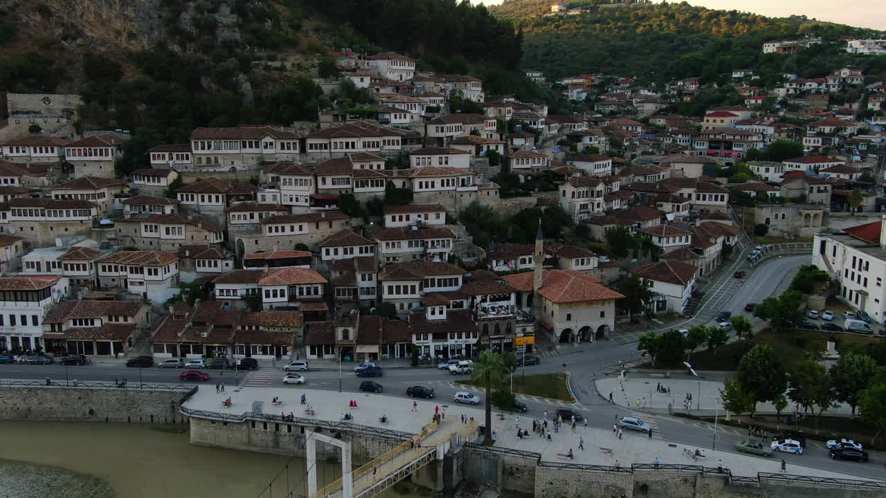 berat, ciudad de albania: vista aérea de las famosas casas y ventanas y de la gente que pasa por el puente de gorica durante la puesta de sol