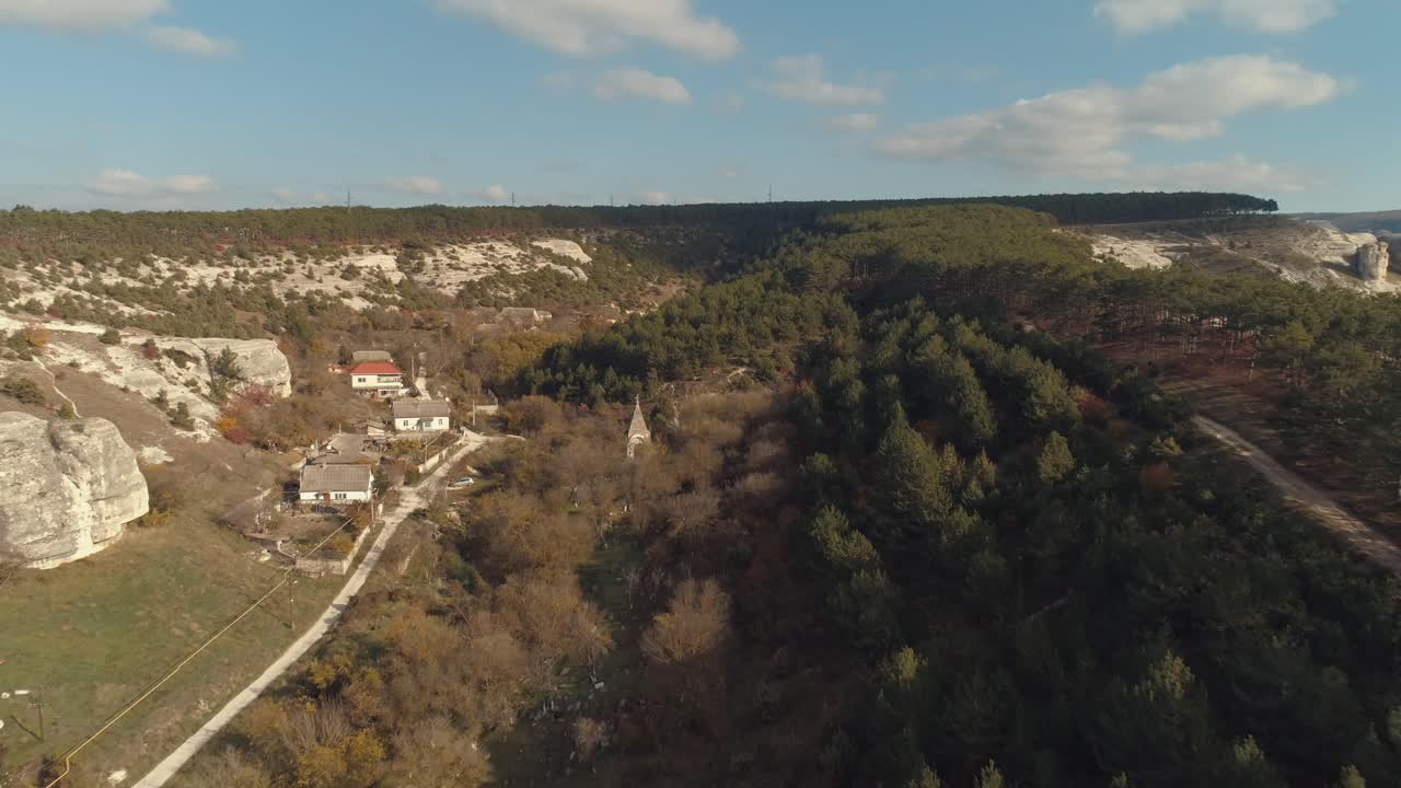 vista aérea de una aldea ubicada en un valle rodeado de montañas y bosques