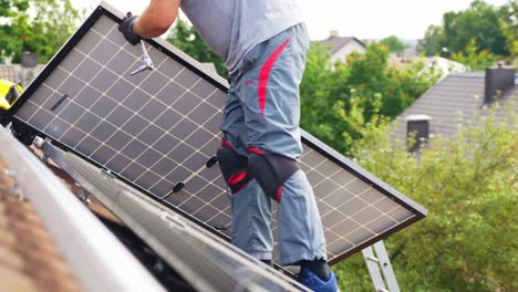 unrecognizable roofer carrying solar panel to install on top of roof, day