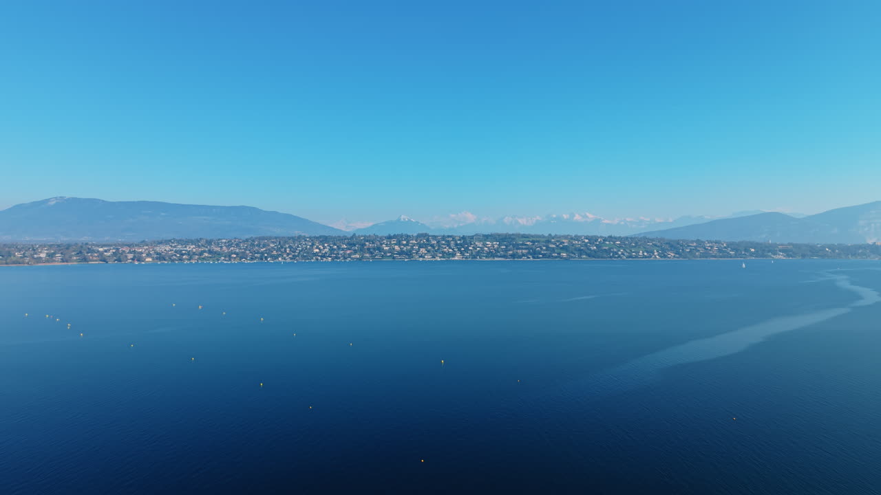 Aerial: Lake Geneva during the day from Vengeron Beach in Geneva, Switzerland, pull out drone shot