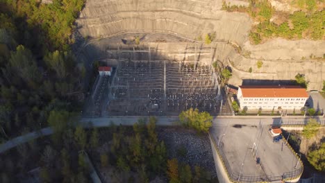 Aerial-establishing-over-electricity-substation-next-to-a-dam-at-sunset