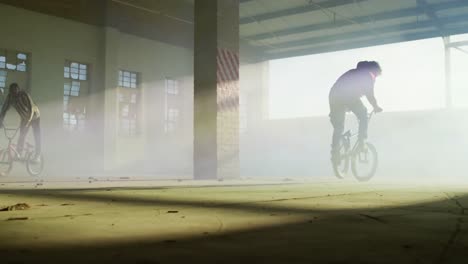 bmx rider in an empty warehouse using smoke grenade