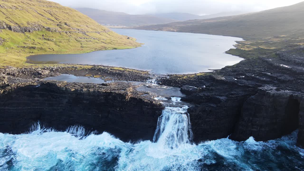 Drone footage passing by the B&oslash;sdalafossur Waterfall near the Leitisvatn Lake, aka the Floating Lake, on the Vagar island in the Faroe Islands