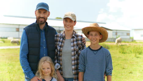 portrait shot of happy cheerful caucasian mother and father with their son and daughter looking and smiling at camera outside the stable