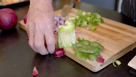 Midsection-of-senior-caucasian-man-cleaning-vegetable-peels-in-kitchen-at-home,-slow-motion