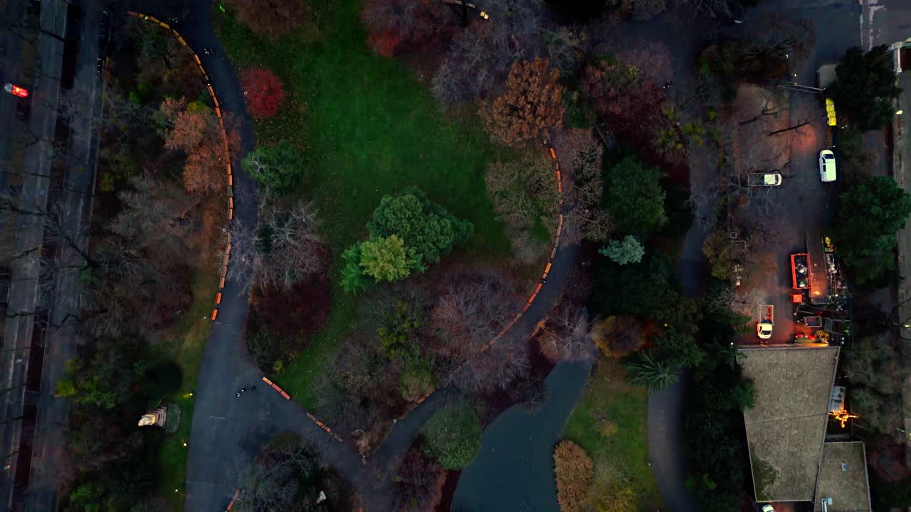 Aerial landscape drone shot panning over Stadtpark in Vienna in winter, highlighting bare trees, winding paths, park lawns, and nearby city buildings under muted winter light