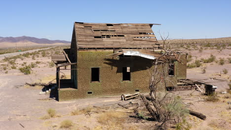 abandoned decrepit run down house sits alone in dry desert area in midday