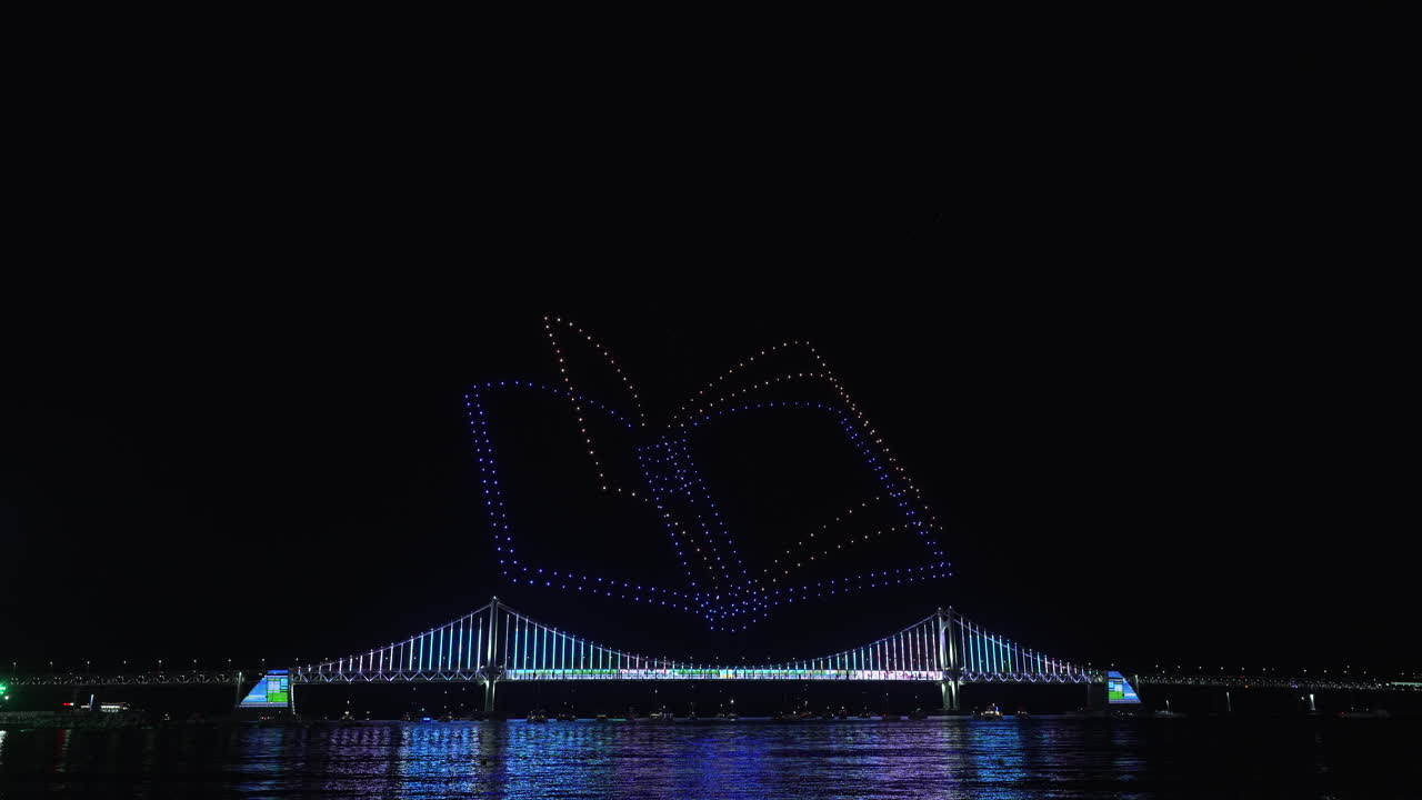 Gwangalli Beach Drone Light Show Above Gwangan Bridge in Busan, South Korea. Glowing Flying Drones Hive Froming A Book with Turning Pages in Night Sky