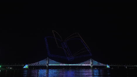 gwangalli beach drone light show above gwangan bridge in busan, south korea. glowing flying drones hive froming a book with turning pages in night sky