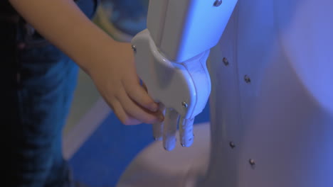 vista de cerca de la mano del niño sostiene la mano de plástico blanco de un robot humanoide en la exposición de robótica en moscú, rusia