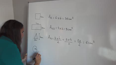 woman writing geometric formulas on a whiteboard