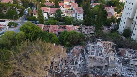 drone in downward view flies over buildings in tel aviv, from a fully destroyed structure to gradually less damaged houses.