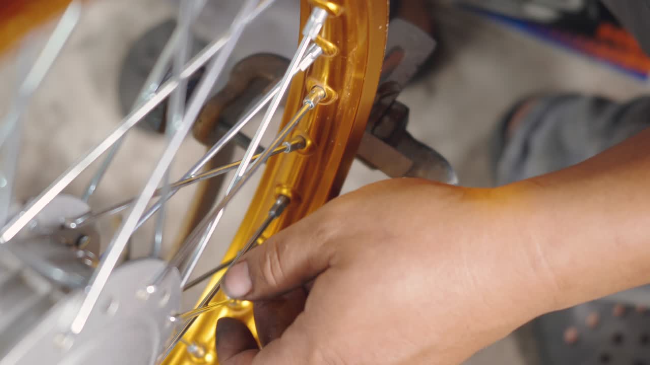 técnico hombre trabajando rueda de motocicleta tiene rayos tejer en herramienta mecánica nueva rueda de acero