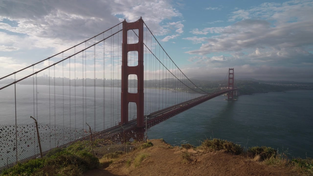 Håndholdt vidvinkelbillede af Golden Gate Bridge og det hængelås-dækkede hegn.